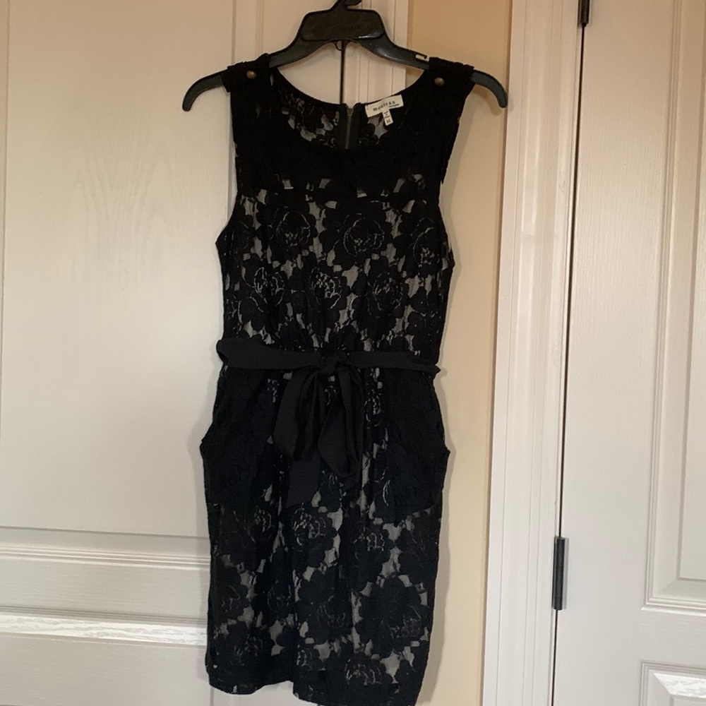 Cute lace sleeveless dress with flesh colored lining and ribbon bow.